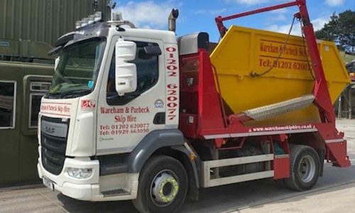 Company branded skip lorry with yellow skip on the loading bay